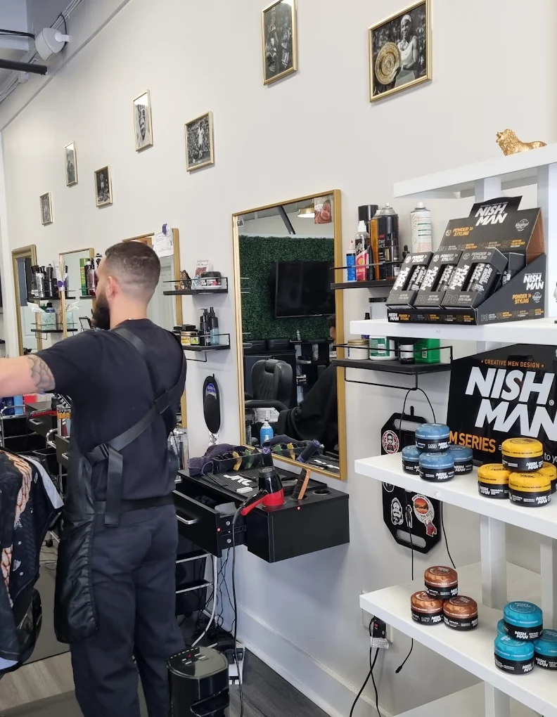Barber at work at his station with product shelves at Victory Barbershop Boca Raton