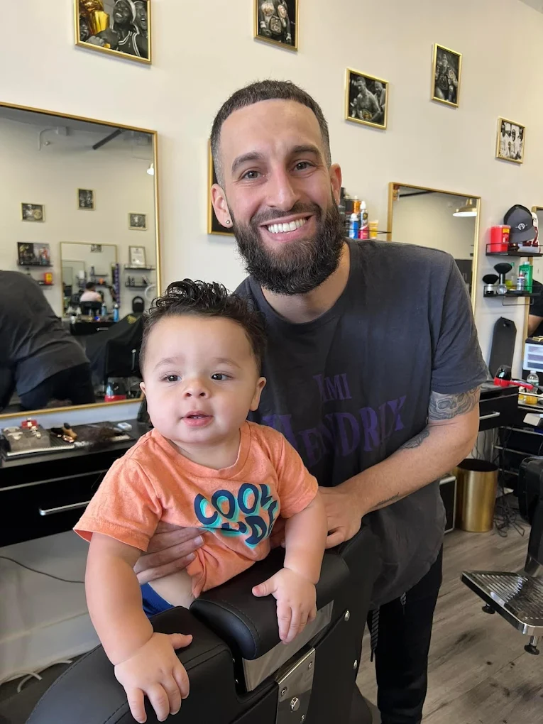 Victory Barbershop barber smiling with a toddler client in Boca Raton