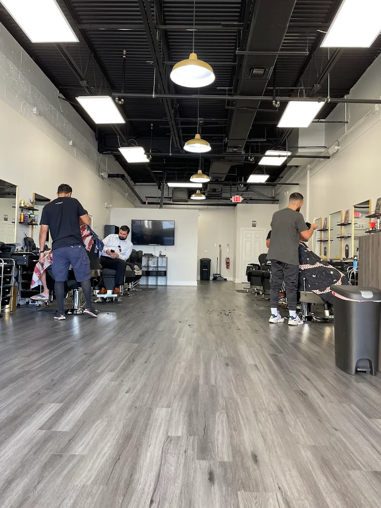 Victory Barbershop shop floor in action under gold pendant lights, Boca Raton