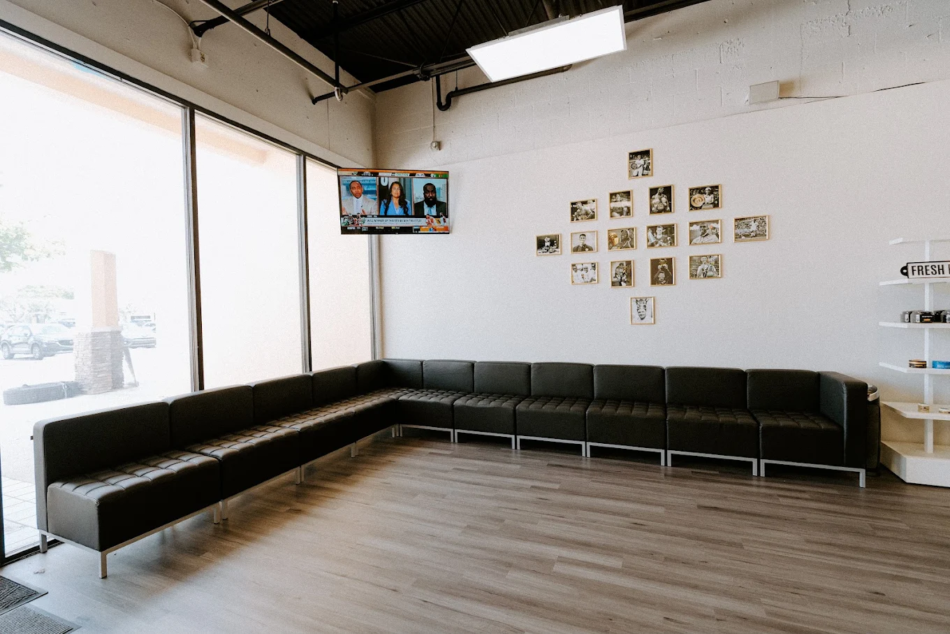 Victory Barbershop waiting area with leather sofa and boxing photo wall in Boca Raton